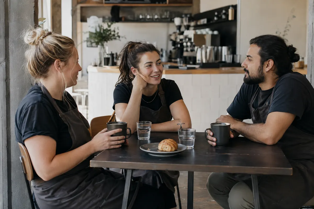Three café employees take a break together at a table between shifts